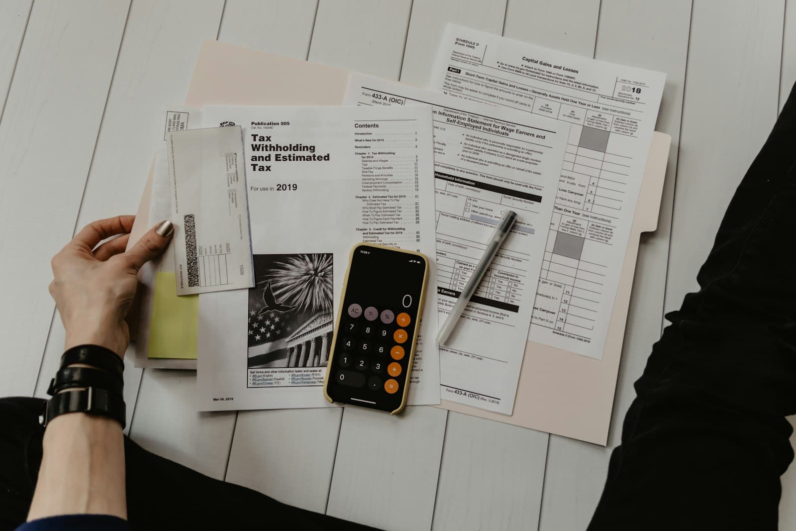 Heir reviewing estate paperwork and tax forms with a calculator before selling inherited property